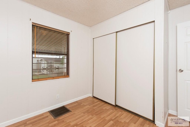 unfurnished bedroom with a textured ceiling, light hardwood / wood-style flooring, and a closet