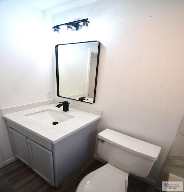 bathroom with hardwood / wood-style flooring, vanity, and toilet