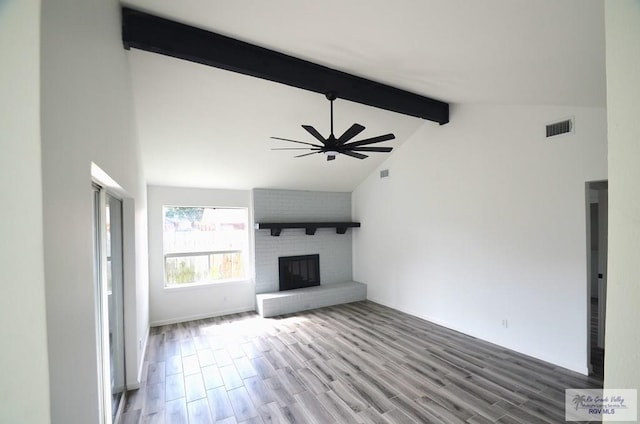 unfurnished living room featuring wood-type flooring, a brick fireplace, ceiling fan, and beam ceiling