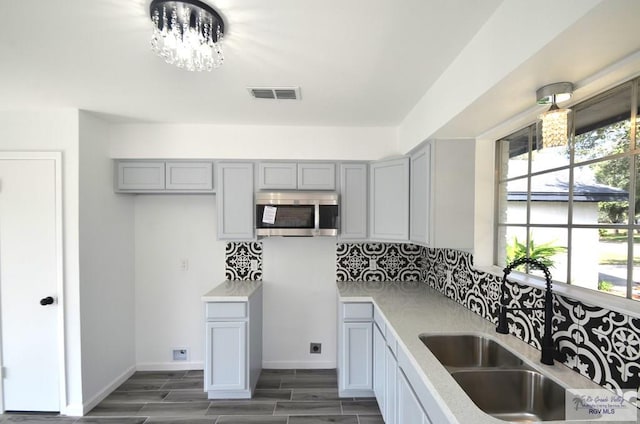 kitchen featuring dark hardwood / wood-style flooring, sink, gray cabinetry, and a notable chandelier