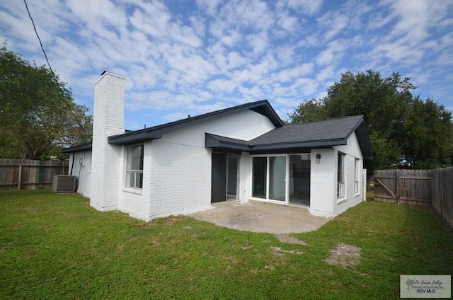 rear view of property featuring a lawn, cooling unit, and a patio