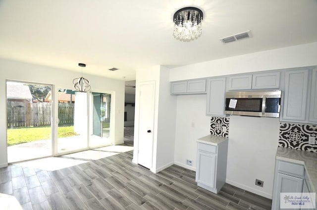 kitchen featuring hardwood / wood-style flooring, decorative light fixtures, gray cabinetry, and an inviting chandelier