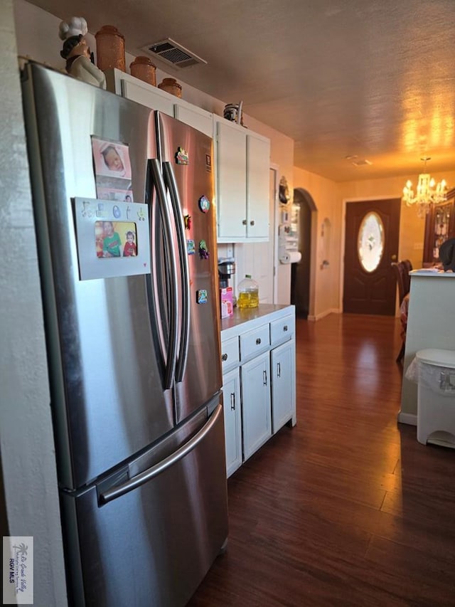 kitchen featuring stainless steel refrigerator, dark hardwood / wood-style flooring, white cabinets, and a chandelier