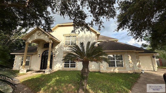 34 Picadilly Cir, Brownsville, TX 78526 - view of front of house with a garage, driveway, a front yard, stucco siding, and roof with shingles