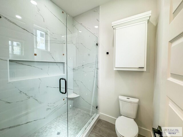 bathroom with a shower with shower door and toilet