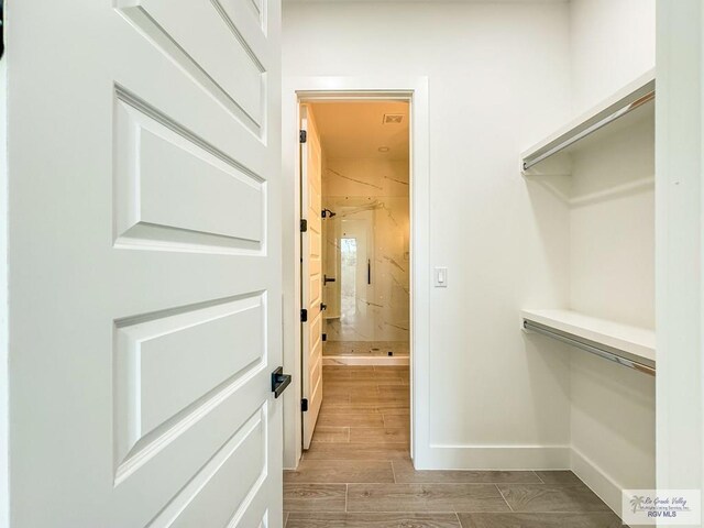 walk in closet with light hardwood / wood-style floors