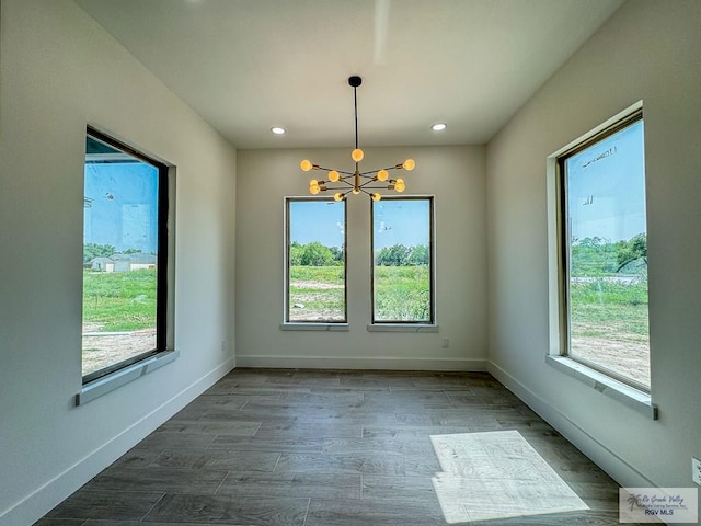 unfurnished dining area featuring hardwood / wood-style floors, plenty of natural light, and a notable chandelier