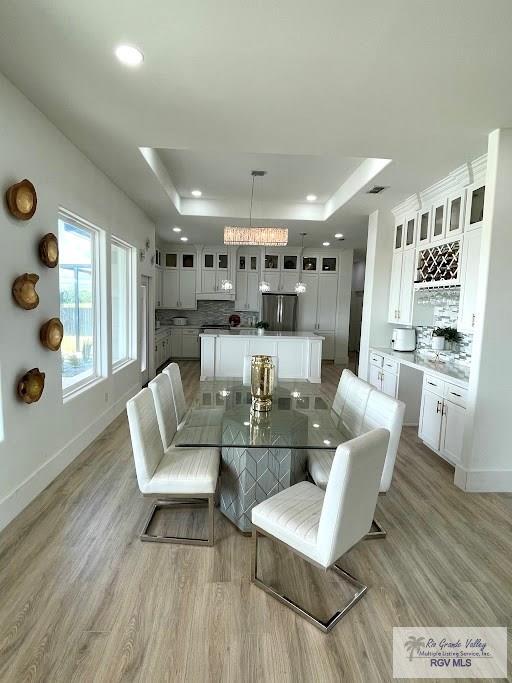 dining space featuring a raised ceiling and light hardwood / wood-style floors