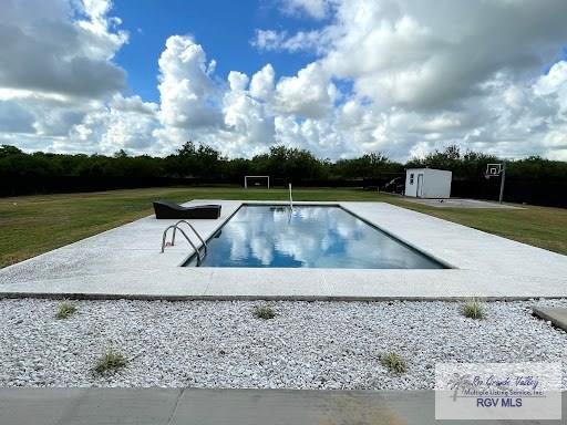 view of swimming pool featuring a storage shed and a yard