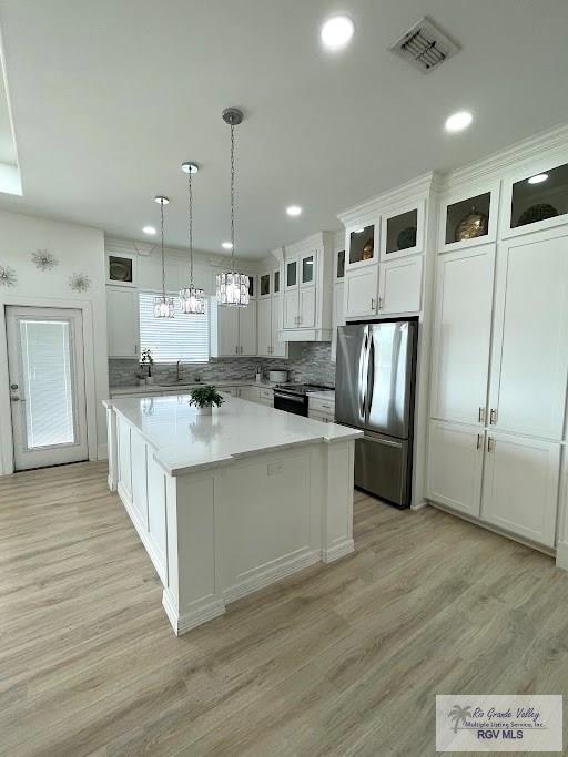 kitchen with white cabinets, a center island, appliances with stainless steel finishes, and pendant lighting