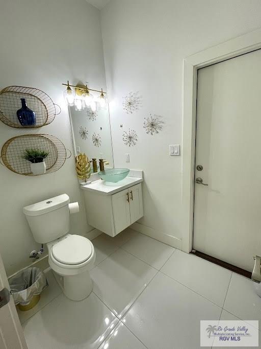 bathroom with toilet, vanity, and tile patterned floors