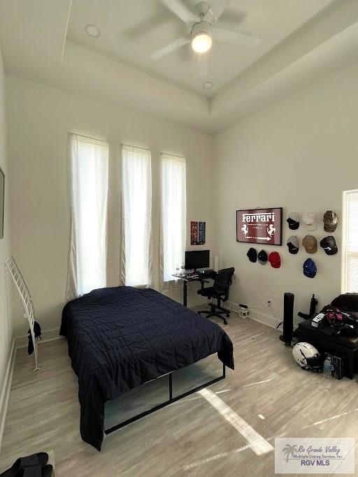 bedroom with a raised ceiling, ceiling fan, and hardwood / wood-style flooring