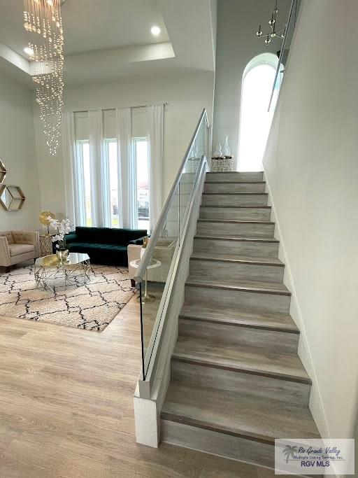 stairway featuring a chandelier, hardwood / wood-style flooring, and a tray ceiling