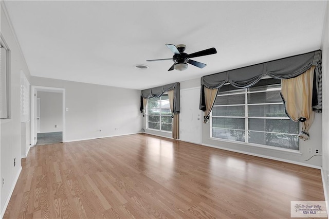 unfurnished living room featuring baseboards, visible vents, a ceiling fan, and wood finished floors