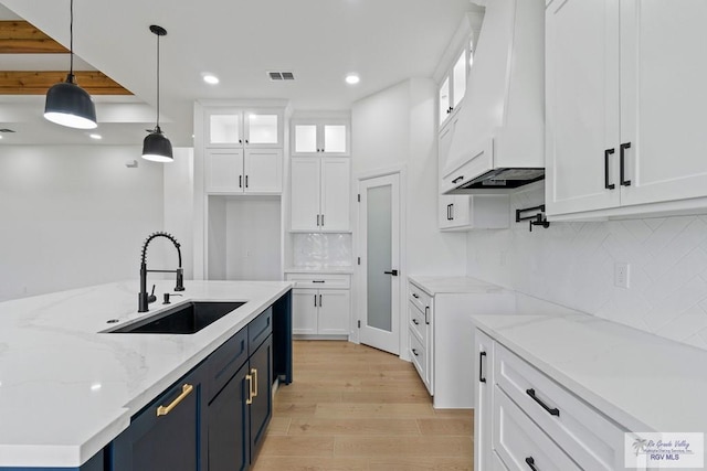 29002 Reynolds Dr # 18, La Feria, TX 78559 - kitchen featuring custom range hood, white cabinets, light wood-type flooring, recessed lighting, and hanging light fixtures
