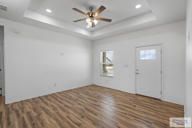 entryway with a tray ceiling, ceiling fan, and dark wood-type flooring