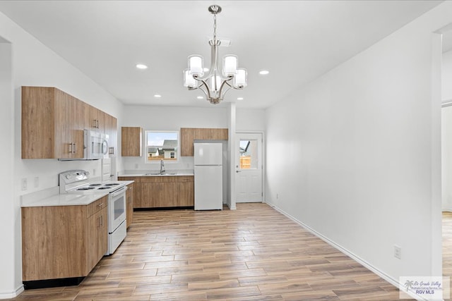 kitchen with white appliances, sink, pendant lighting, light hardwood / wood-style flooring, and a chandelier