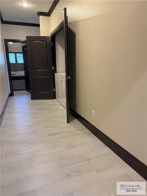 hallway featuring light wood-type flooring, washing machine and dryer, and crown molding