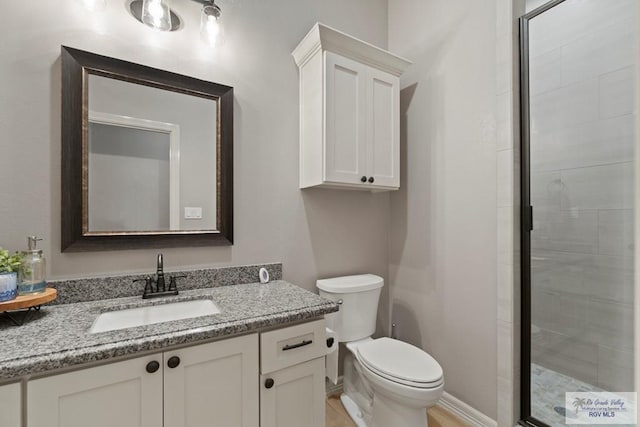 bathroom with walk in shower, vanity, and toilet