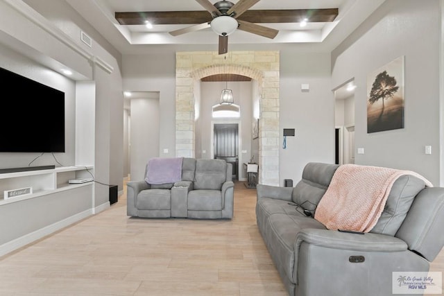 living room featuring ceiling fan, beam ceiling, light wood-type flooring, and coffered ceiling