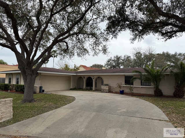 ranch-style house featuring a garage, concrete driveway, and brick siding