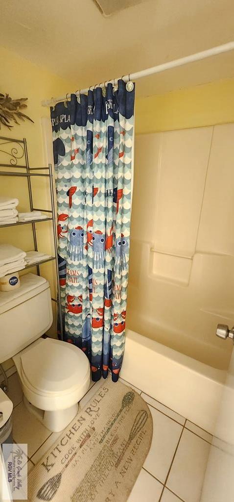 bathroom featuring tile patterned floors, toilet, and shower / bath combo with shower curtain