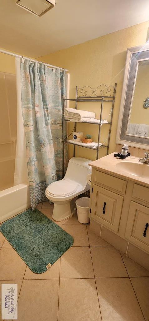 full bathroom featuring toilet, tile patterned flooring, vanity, and shower / tub combo with curtain