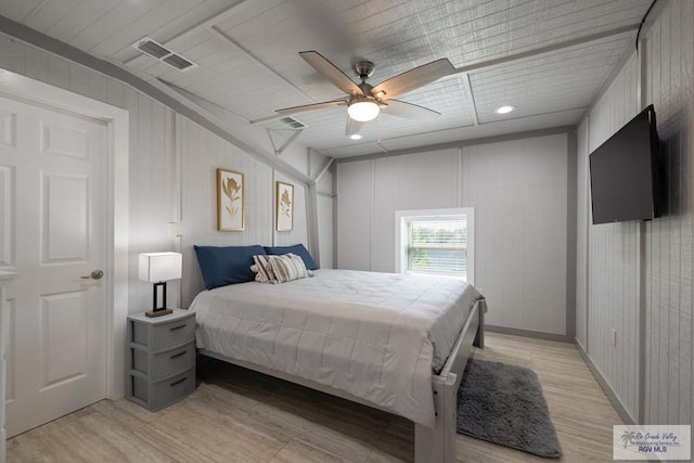 bedroom featuring ceiling fan, wood walls, and light wood-type flooring