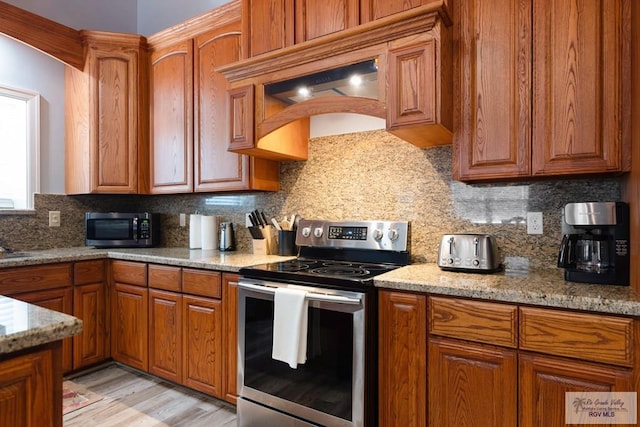 kitchen featuring backsplash, light hardwood / wood-style floors, light stone countertops, and stainless steel appliances