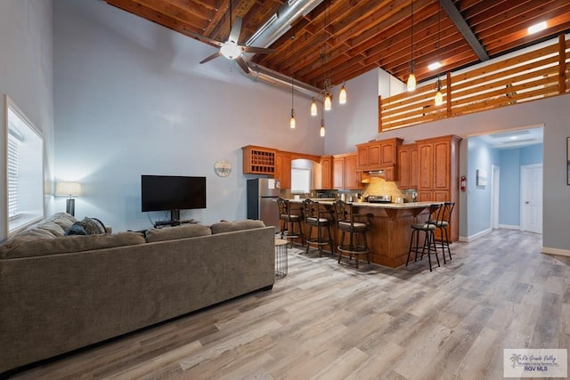 living room with beamed ceiling, a towering ceiling, light hardwood / wood-style floors, and wood ceiling