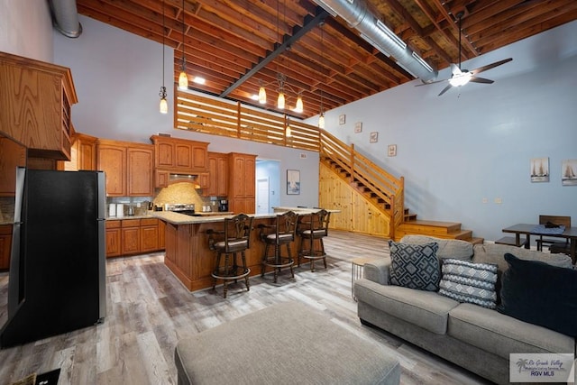 living room featuring ceiling fan, light hardwood / wood-style floors, and a high ceiling