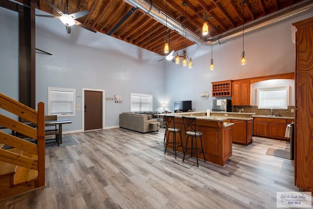 kitchen with a kitchen breakfast bar, ceiling fan, light wood-type flooring, and a high ceiling