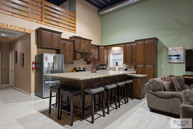 kitchen with dark brown cabinetry, a kitchen breakfast bar, a kitchen island, custom range hood, and appliances with stainless steel finishes