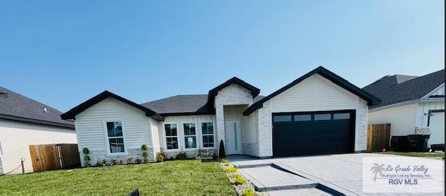 825 Milania Dr, La Feria, TX 78589 - view of front of home with a garage, concrete driveway, and stone siding