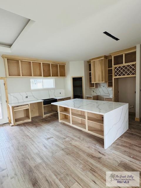 825 Milania Dr, La Feria, TX 78589 - kitchen featuring open shelves, light wood-type flooring, a kitchen island, and light stone counters