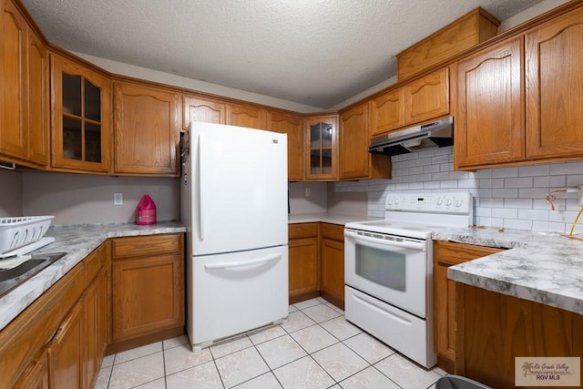 kitchen featuring backsplash, a textured ceiling, light tile patterned flooring, and white appliances