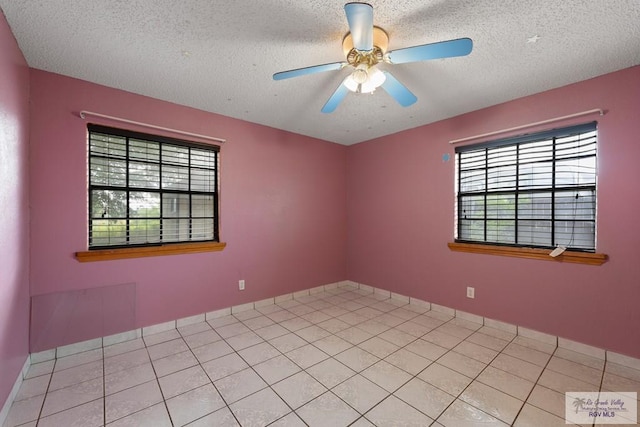 empty room featuring light tile patterned floors, a textured ceiling, a wealth of natural light, and ceiling fan