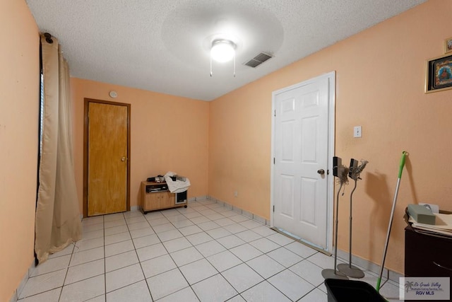 spare room with a textured ceiling and light tile patterned flooring