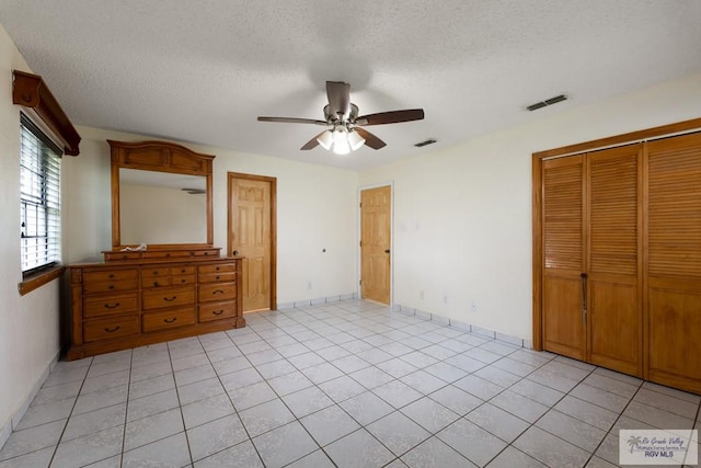 unfurnished bedroom with ceiling fan, a closet, light tile patterned flooring, and a textured ceiling