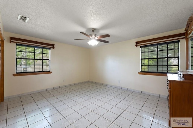 spare room with ceiling fan, plenty of natural light, light tile patterned floors, and a textured ceiling