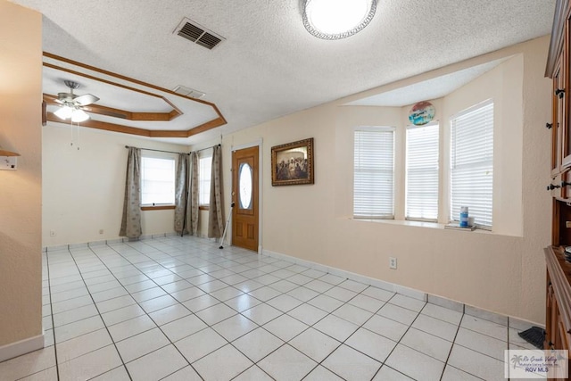 entryway with ceiling fan, light tile patterned floors, a textured ceiling, and a tray ceiling