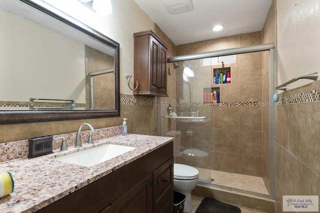 bathroom with vanity, tile patterned flooring, toilet, tile walls, and an enclosed shower