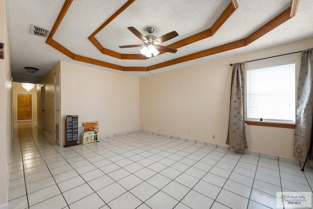 spare room featuring a raised ceiling, ceiling fan, ornamental molding, a textured ceiling, and light tile patterned flooring