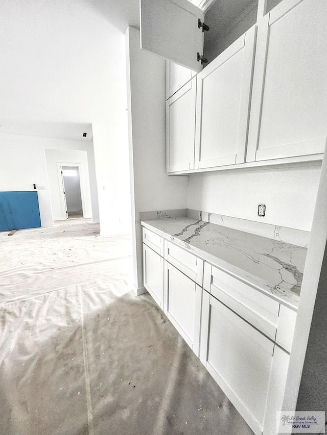 kitchen featuring white cabinetry, light stone countertops, and concrete floors