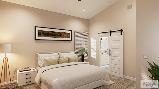 bedroom with vaulted ceiling, ensuite bathroom, and a barn door