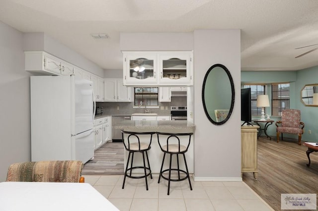 kitchen with white cabinetry, sink, a breakfast bar area, backsplash, and stainless steel appliances