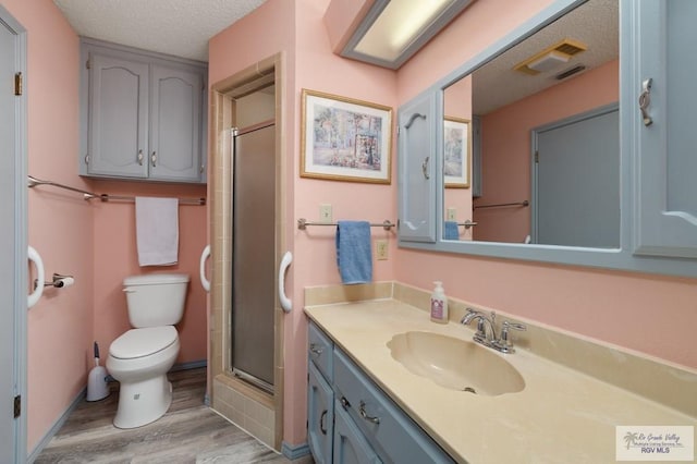 bathroom with hardwood / wood-style flooring, vanity, walk in shower, toilet, and a textured ceiling