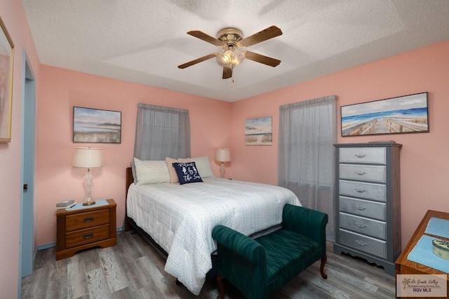 bedroom featuring hardwood / wood-style flooring, ceiling fan, and a textured ceiling