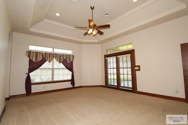 empty room with carpet flooring, a tray ceiling, and ceiling fan