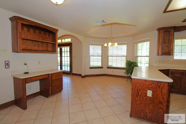 kitchen featuring a kitchen island, a chandelier, decorative light fixtures, a tray ceiling, and light tile patterned floors